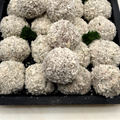 A black tray filled with breaded round CHICKEN GARLIC BALLS with a few small green herb garnishes, photographed from above on a light surface.