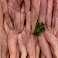 Raw chicken breast fillets arranged vertically, with a small green parsley garnish in the center, photographed close-up.