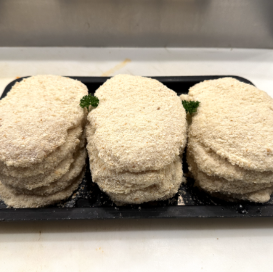 Three stacks of round, breaded chicken schnitzel, arranged on a black tray with small green garnish pieces on a white countertop.