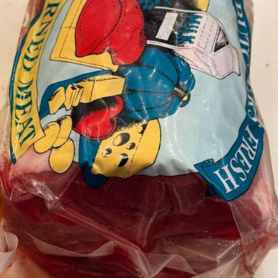 A packaged piece of CORNEDSILVER SIDE in clear plastic wrapping with a colorful printed label featuring cartoon graphics and text, photographed on a light surface.