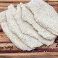 Four thick, rectangular, breaded chicken schnitzels stacked on a wooden cutting board with seasoning, rosemary, and a garlic clove. Available at Robina Quality Meats