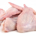 Raw chicken wings piled together on a plain white background.
