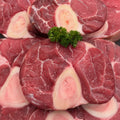 Raw OSSO BUCCO with bone, arranged closely together and garnished with a small green parsley sprig in the center.