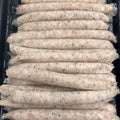 Multiple raw sausage links arranged in rows inside a black plastic tray.